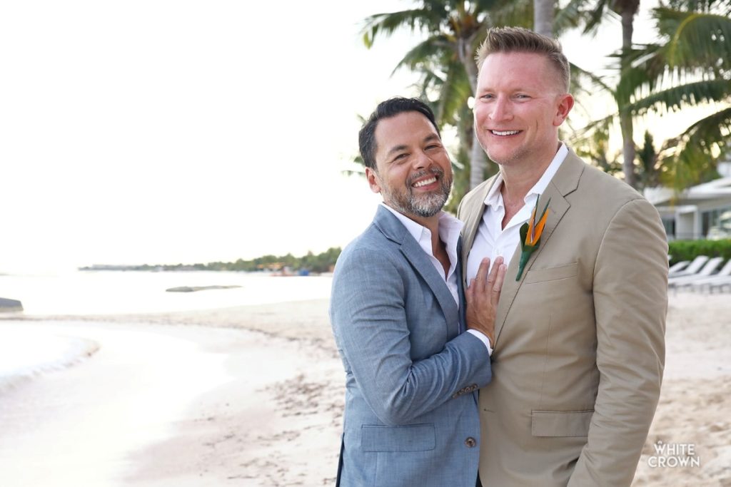 same sex wedding couple posing at the beach after their wedding ceremony 