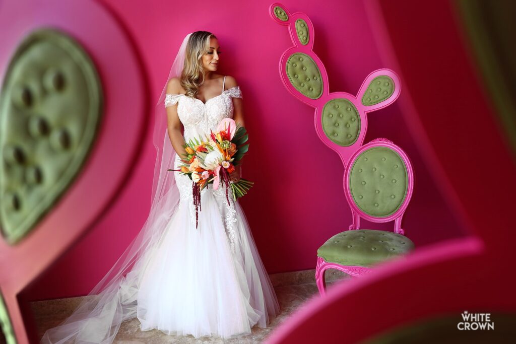 stunning bride holding a flower bouquet against a brigth pink wall