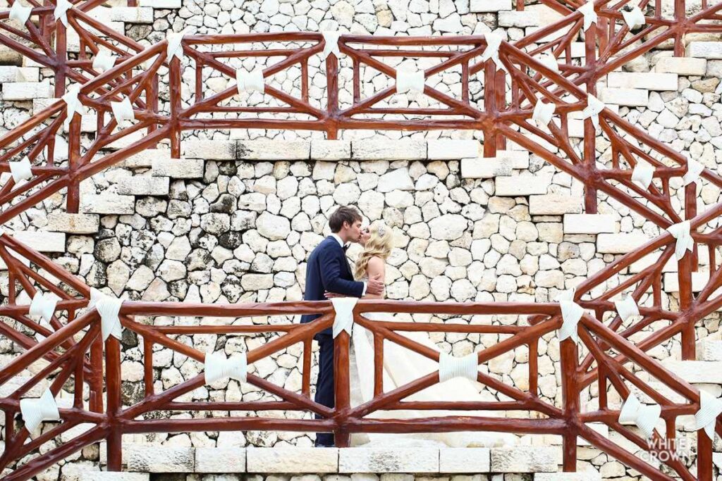 couple kissing at the stairs of the wedding chapel at hotel xcaret mexico